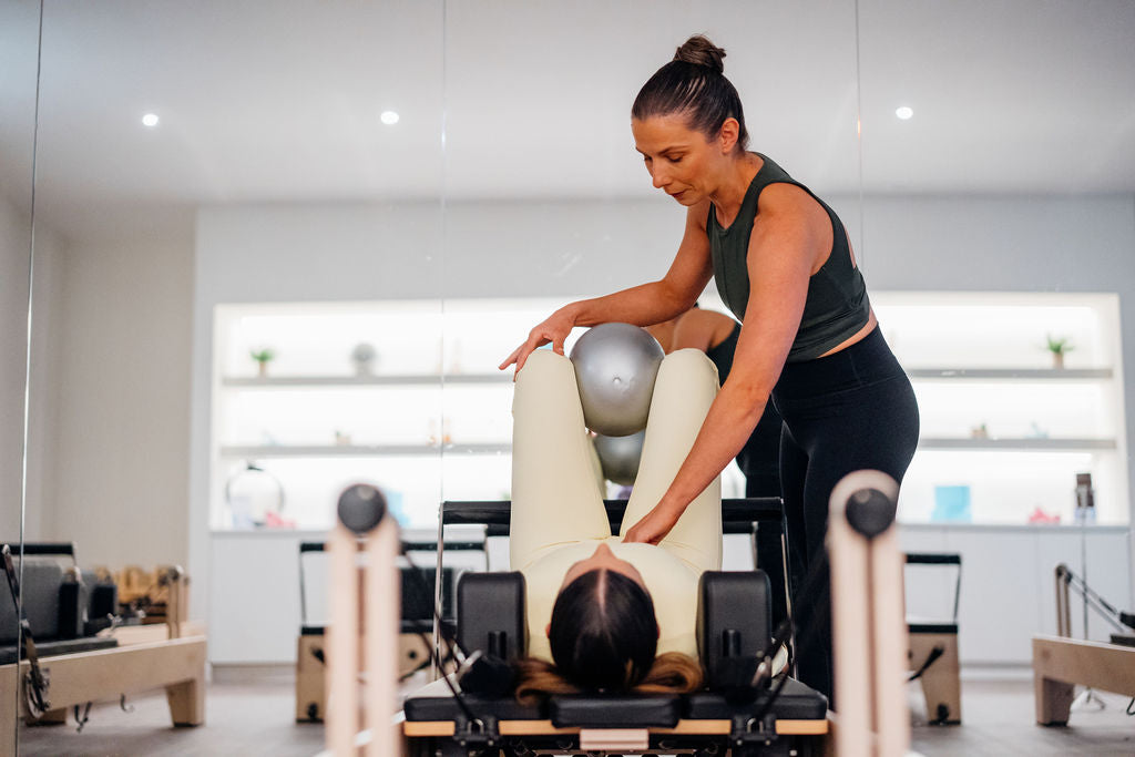 Pilates student holding the rope of a reformer bed