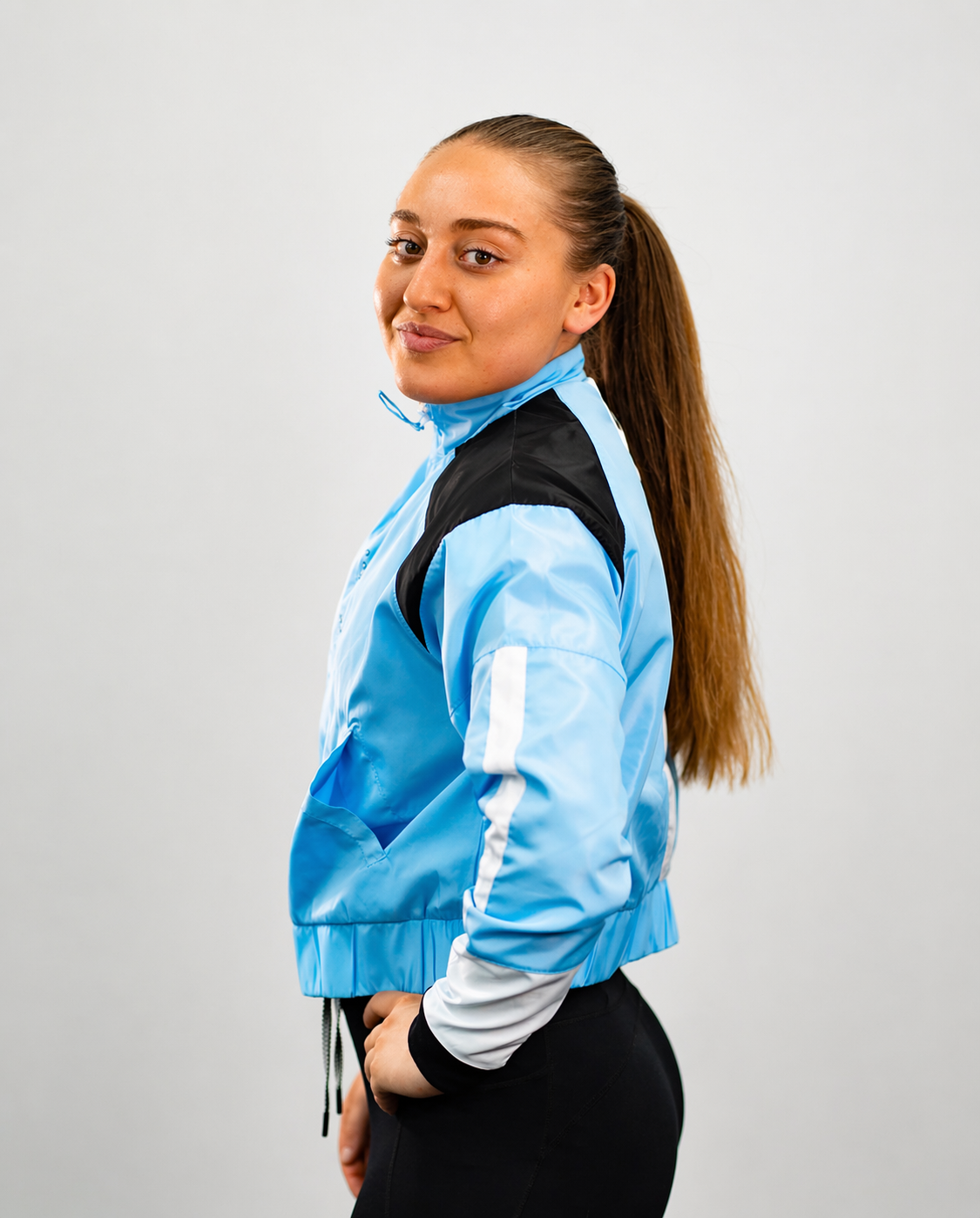 Yazmin Dann wearing a light blue jacket with a black back panel on a plain background