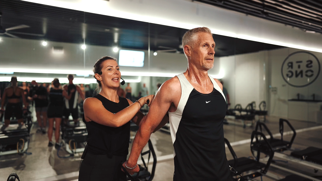 Diana Coffey teaching a male student on a reformer pilates bed in a STRONG studio