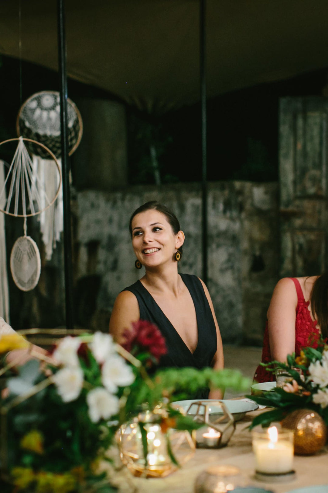 Diana Coffey sitting at a table with floral arrangements and candles in a dimly lit room.