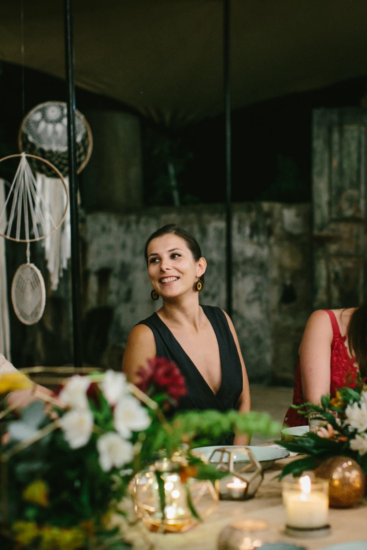 Diana Coffey sitting at a table with floral arrangements and candles in a dimly lit room.
