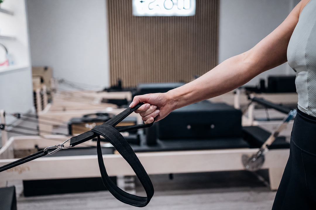 Pilates student holding the rope of a reformer bed