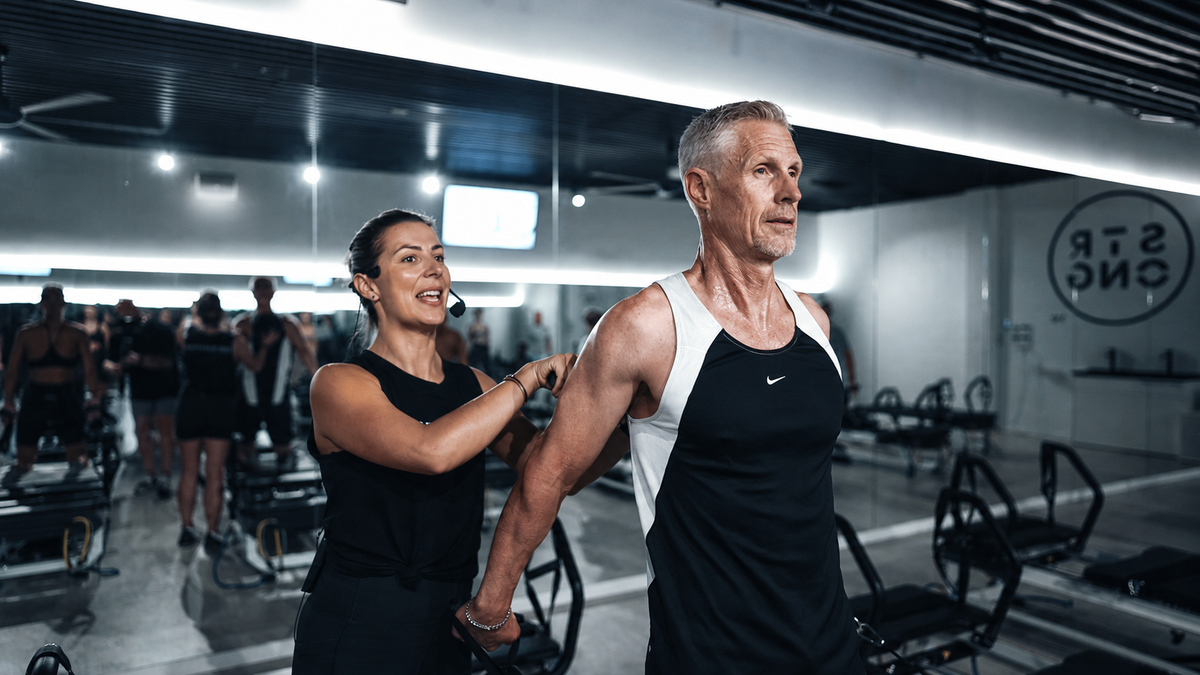 Diana Coffey instructing a male student on a reformer pilates bed at 'STRONG'