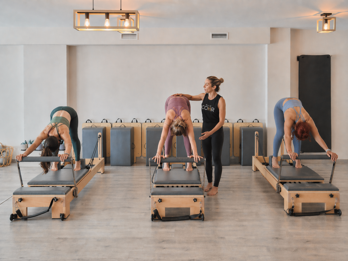 Pilates reformer class in a studio with three participants and instructor Diana Coffey.