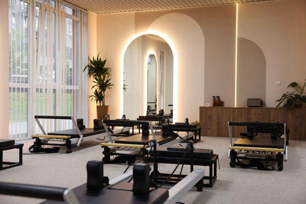 Pilates reformers in a modern studio with large windows and neutral decor.