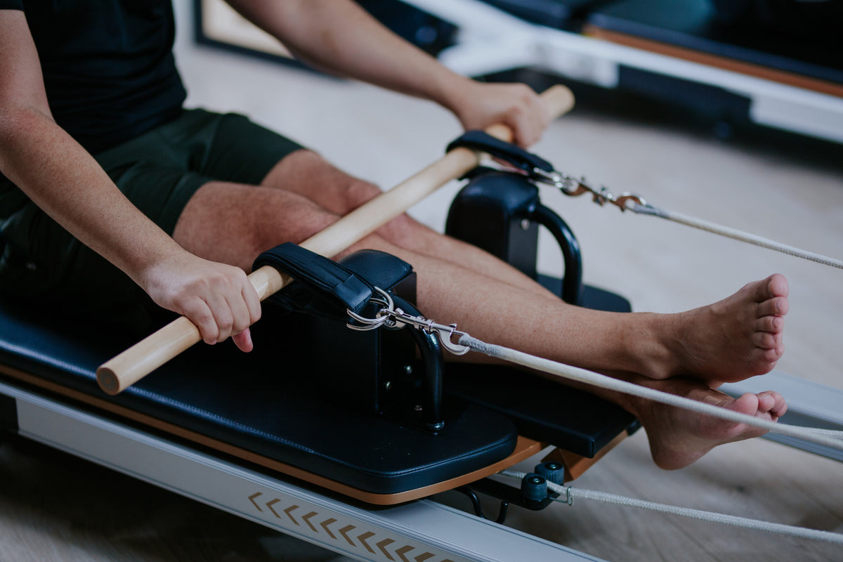Man using a Pilates reformer machine in a gym setting