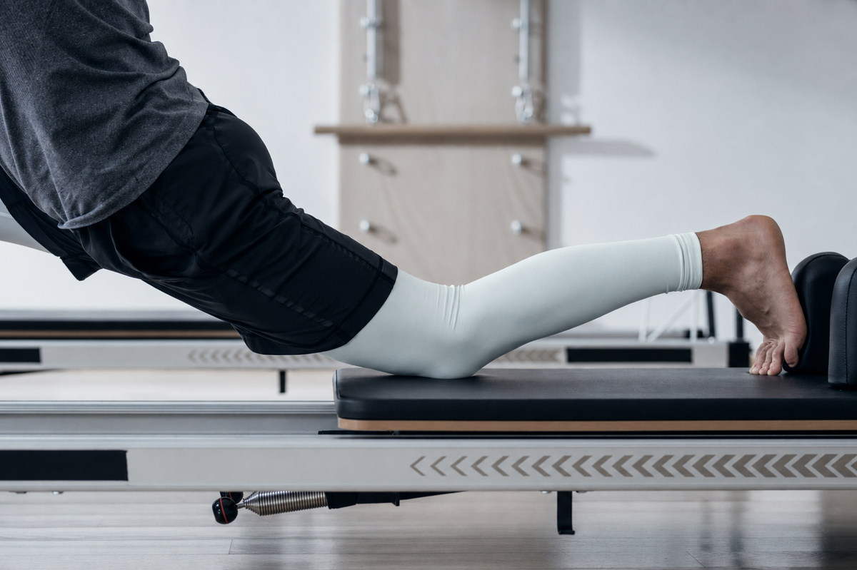 Man using a Pilates reformer machine in a studio setting