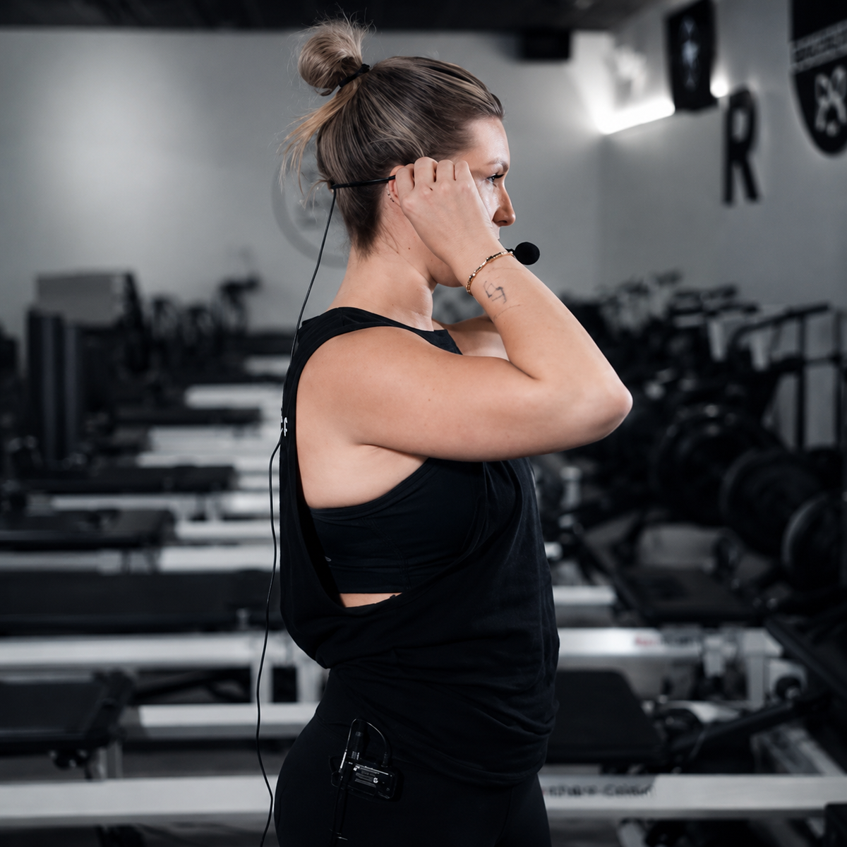 Paige World — former Strong Pilates instructor adjusting her microphone in studio