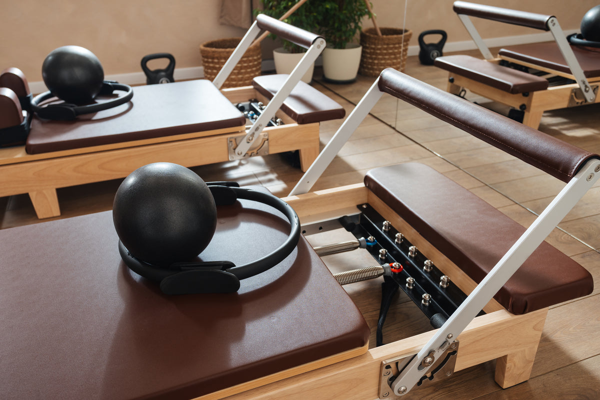 Diana assisting a student in quadruped on a reformer bed.
